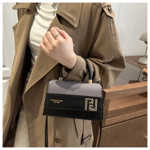 Detail showing high-quality gray fabric and black leather contrast on a small square bag