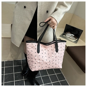 Detail of pink quilted tote bag featuring small black bows and stylish leather handles