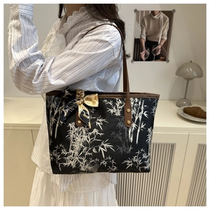 Detail of bamboo print tote bag with brown leather handles and decorative floral silk scarf