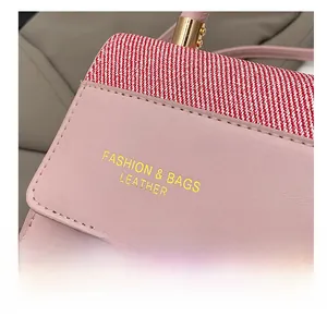 Détail du sac à main en cuir rose avec lettrage doré et garniture en tissu rayé rouge et blanc