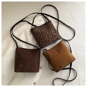 Three bucket bags in leopard print and suede finishes displayed on white fabric background