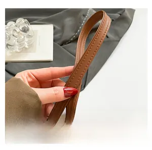 Détail de la poignée en cuir marron avec coutures fines sur un sac peluche léopard