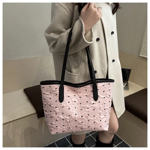 Close-up of pink quilted tote bag featuring black bow patterns and long shoulder straps