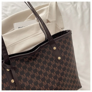 Détail du grand sac cabas marron foncé avec rivets dorés et imprimé à motifs en M