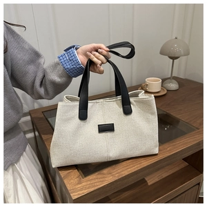 Close-up of minimalist canvas tote bag with black leather handle in lifestyle setting