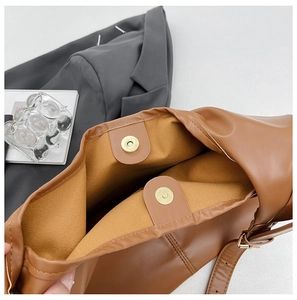 Detail of magnetic snap closure and fabric lining on brown PU leather bucket bag