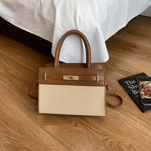 Sac à main élégant en cuir marron et tissage beige posé sur un parquet chaleureux