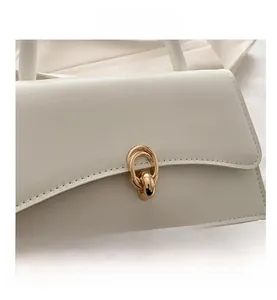 Nahaufnahme der weißen Ledertasche mit goldenem Ringverschluss und feiner Nahtverarbeitung