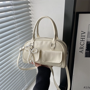 Retro cream Boston bag with double pockets and pearl bow charm shown in hand