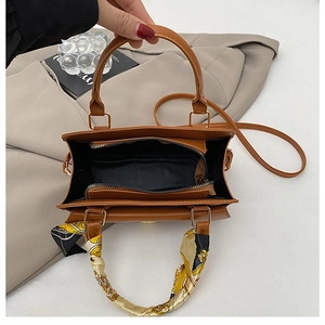 Detail view of brown leather handbag interior with middle zipper compartment and scarf handle