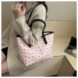 Detail of pink quilted tote bag with black bow accents and long leather handles