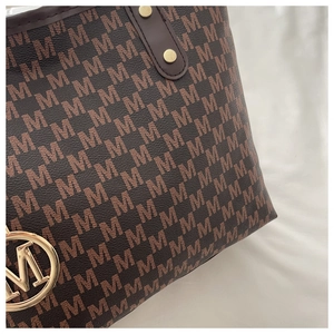 Gros plan du sac cabas marron avec motif monogramme M et finitions métalliques dorées