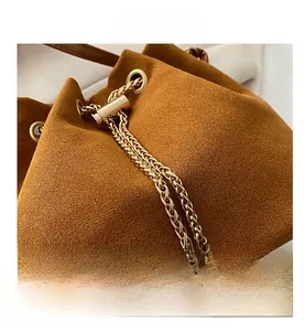 Detail of brown suede bucket bag with gold chain drawstring and pearl accents