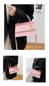Détail du sac bandoulière en cuir rose avec boucle en métal doré et lettrage fashion