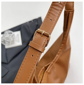 Detail of adjustable golden metal buckle on a caramel brown leather shoulder bag strap