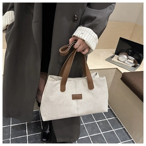 Chic canvas tote bag with brown leather straps held by a model in a cozy interior setting