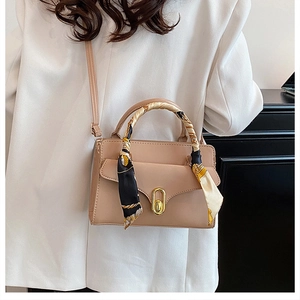 Détail du sac à main en cuir rose avec boucle dorée et foulard en soie imprimé décoratif