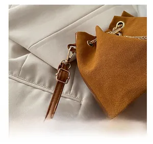Detail of brown suede bucket bag featuring premium gold-tone metal hardware and leather strap