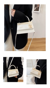 Détail du sac à main en cuir blanc avec boucle géométrique dorée et texte élégant