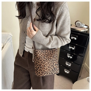 Detail view of stylish leopard print bucket bag with brown leather strap and retro texture