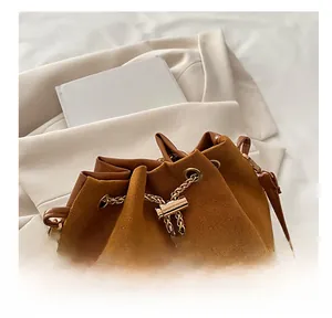 Detail of caramel suede bucket bag with gold chain strap and premium leather trim
