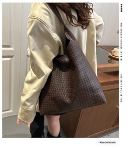 Detail of a deep brown woven tote bag featuring an intricate intrecciato pattern design