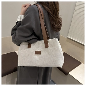 Close-up of canvas tote bag showing the textured fabric and brown leather handle strap