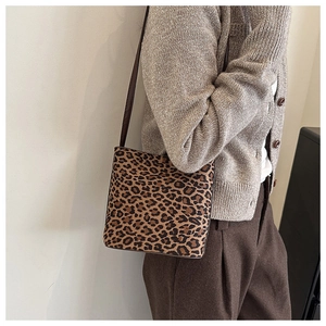 Close-up of leopard print suede shoulder bag with thin brown leather strap on model