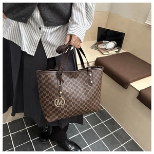 Détail du grand sac cabas marron foncé avec imprimé M et breloque en métal rond