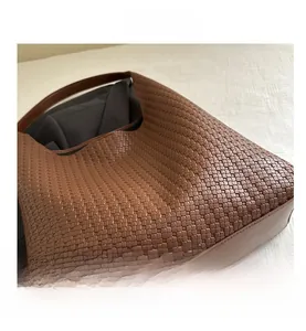 Detail view of brown woven tote bag featuring classic Intrecciato leather texture