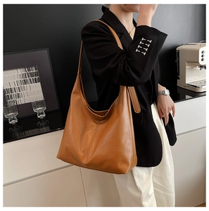Close-up of minimalist large brown tote bag showing supple PU leather texture and stitching