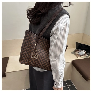 Détail du sac cabas marron avec motif M vintage et pendentif doré en métal chic