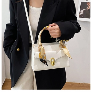 Détail d'un sac à main blanc avec fermoir doré et poignée décorée d'un foulard en soie
