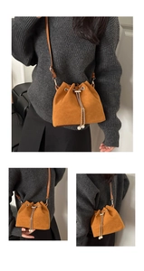 Macro detail of brown suede bucket bag featuring gold chain drawstring and pearl charms