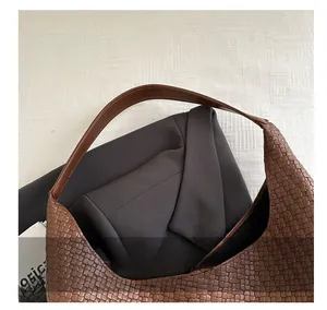 Detail view of smooth leather handle and dark brown woven texture on a tote bag