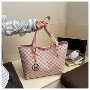 Détail du cabas rose avec imprimé monogramme M et pendentif logo doré pour le bureau
