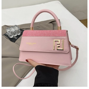 Détail du sac à main en cuir rose avec rabat à rayures rouge et blanc et boucle dorée