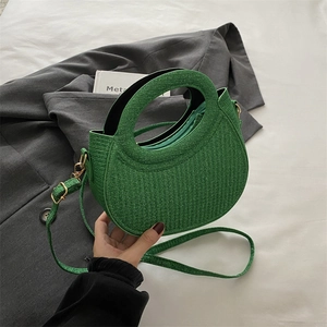 Green crescent crossbody bag with top handle and textured glitter finish on grey blazer