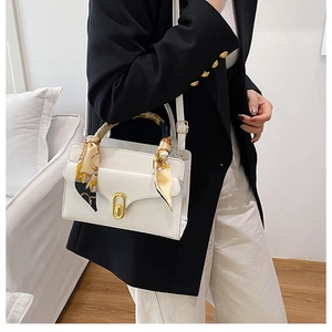 Détail du sac à main en cuir blanc avec poignée en foulard de soie et fermoir doré