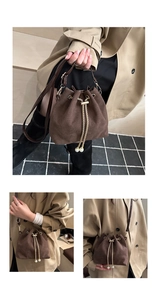 Detail of brown suede bucket bag featuring golden chain drawstring and pearl charms