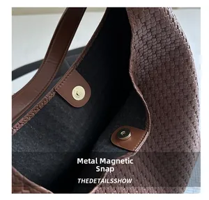 Detail view of the golden magnetic snap closure and woven texture on a brown tote bag