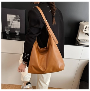 Brown leather tote bag featuring a wide adjustable shoulder strap with silver buckle