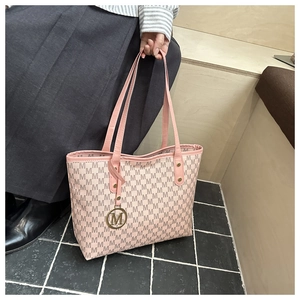 Détail du sac cabas rose à monogramme avec pendentif M doré et texture cuir premium