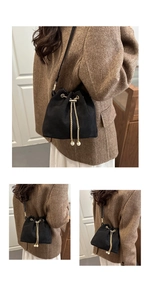 Detail of matte black bucket bag with gold chain drawstring and pearl charm accents