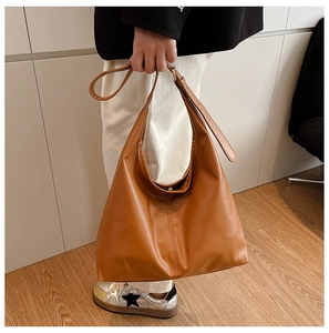 Detail of adjustable wide shoulder strap on a brown leather minimalist tote bag