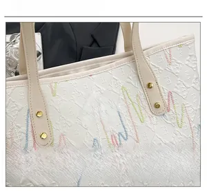Detail of white leather tote with colorful wave embroidery and gold rivet hardware