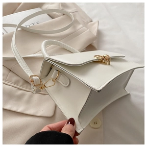 Detailansicht der weißen Tasche mit goldenem Schloss und verstellbarem Riemen im Minimal-Stil