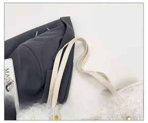 Detail of reinforced leather strap with gold rivets and embroidery on cream tote bag