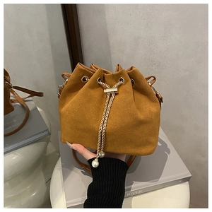 Detail of brown suede bucket bag with gold chain drawstring and pearl accents
