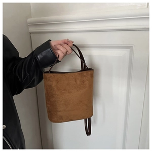 Detail view of brown matte bucket bag showing retro suede texture and leather strap
